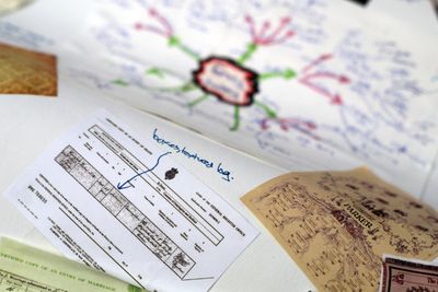 Printouts of birth certificates and family trees stuck on white paper, with hand-written notes around them
